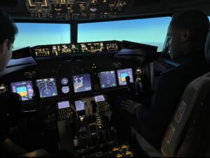 Carlos is sitting in a 737 simulator learning how to fly at a pilot careers seminar.